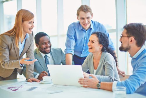 Group of business partners looking at smiling female explaining her ideas at meeting